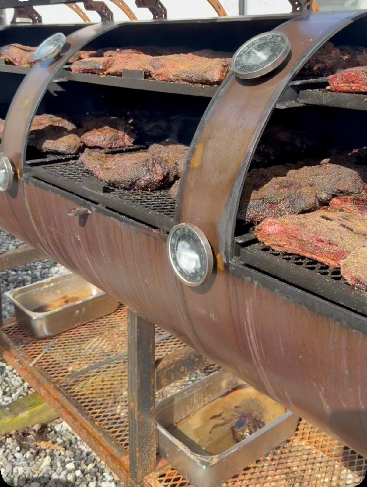 Nessie, a loaded offset smoker with racks of brisket and beef ribs behind open lids